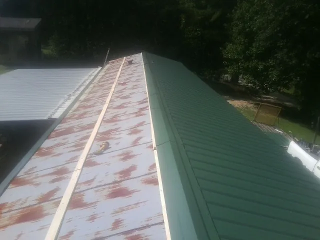 Old rusted panels beside newly installed green metal roofing — Wind Damage Roof Repair by Roofing Brothers in Montoursville