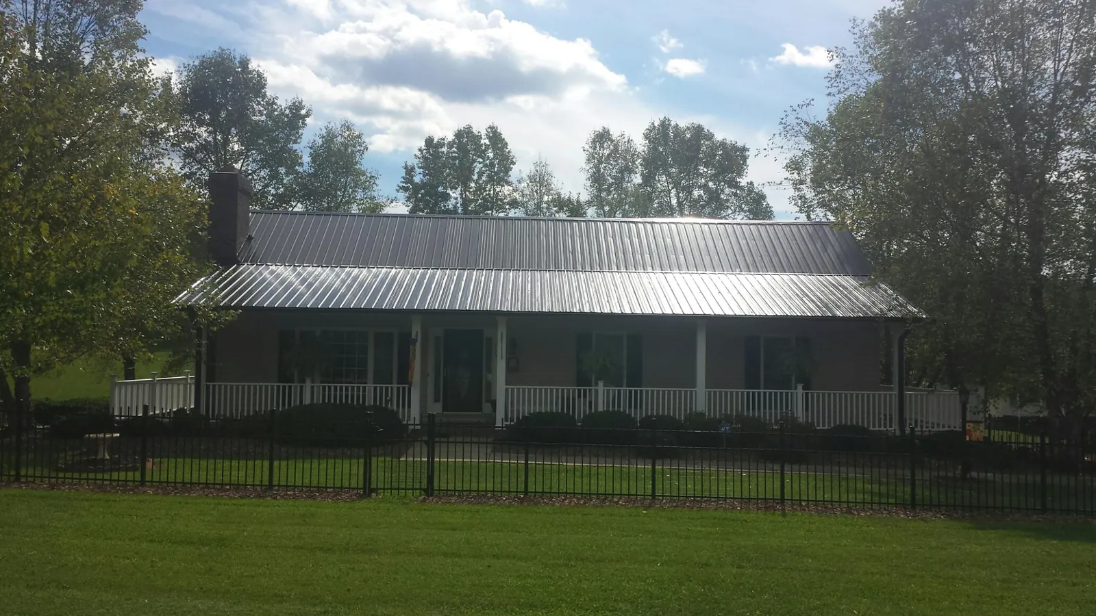 Gray metal roof on a brick ranch with a full width front porch — Gutter Guard Installation work by our crew in Montoursville