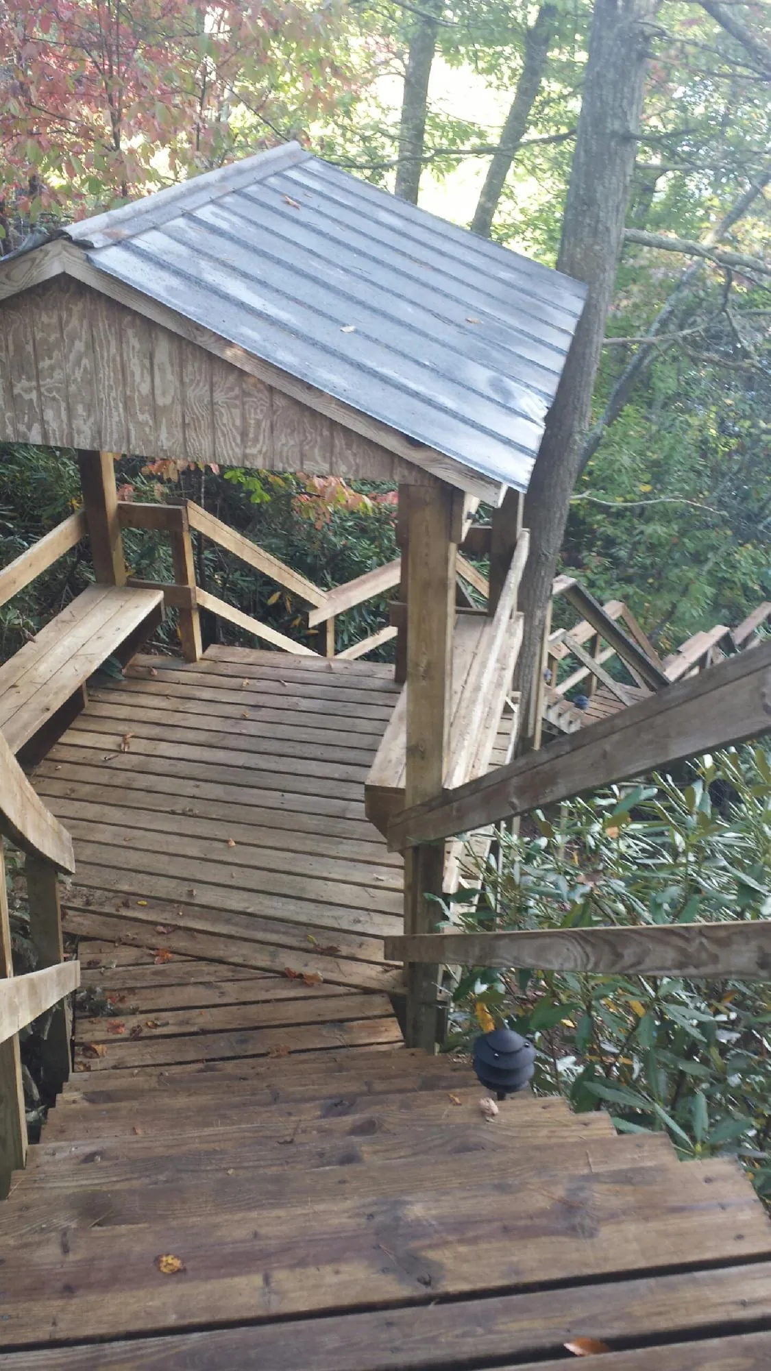 Metal roofed shelter over wooden steps on a wooded walkway — Skylight Repair & Installation work by our crew in Montoursville