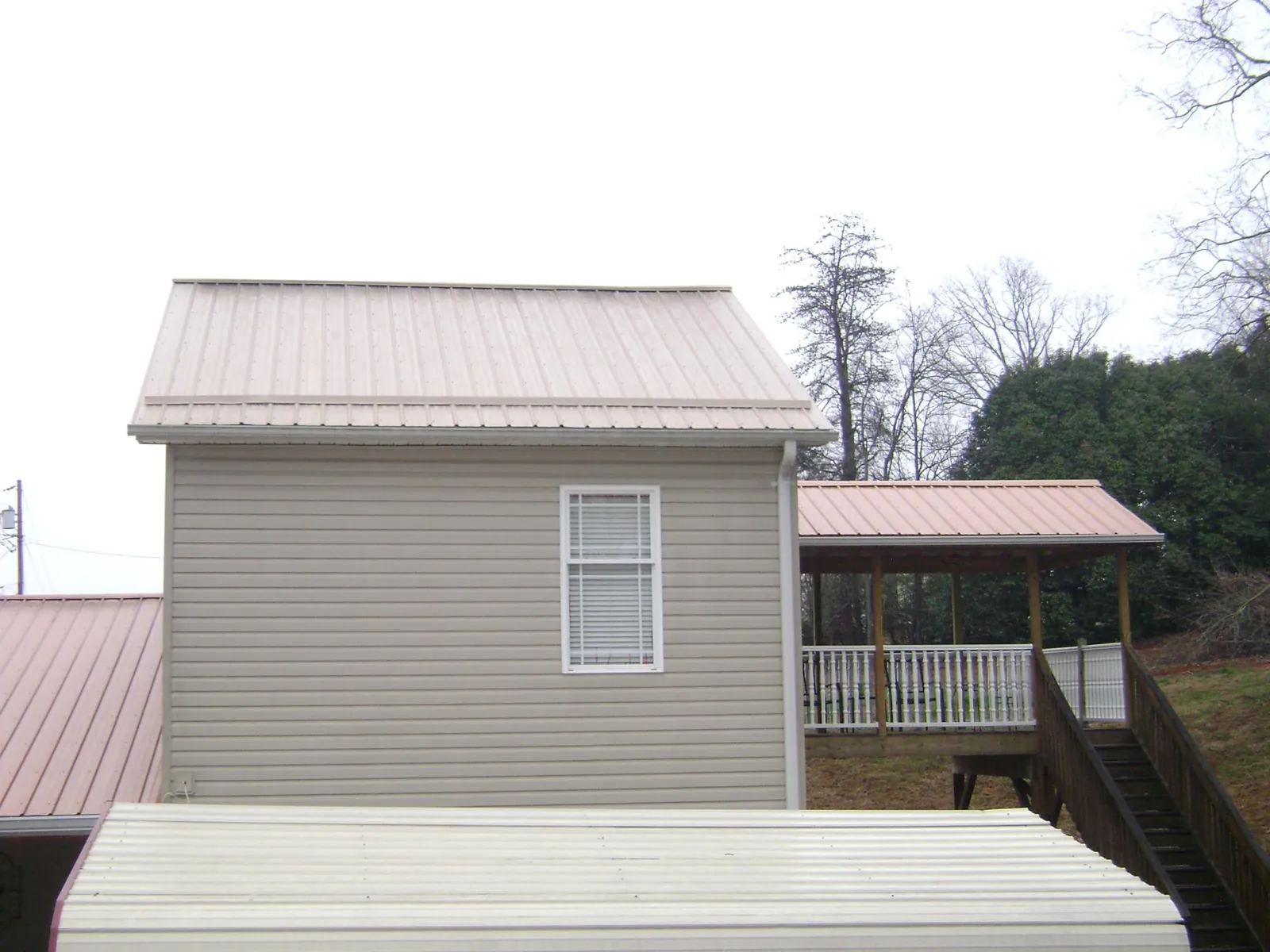 Tan metal roofs on a two story addition and attached porch, from a Roof Replacement job in Montoursville