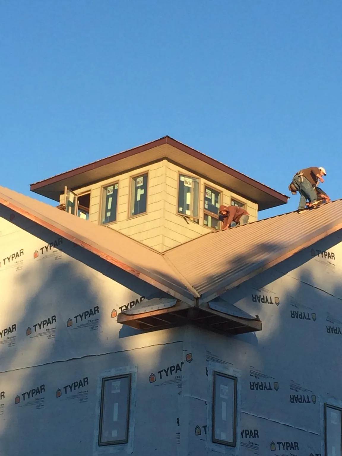 Roofers working around a rooftop cupola on a new metal roof at sunset — Roof Waterproofing in Montoursville by Roofing Brothers